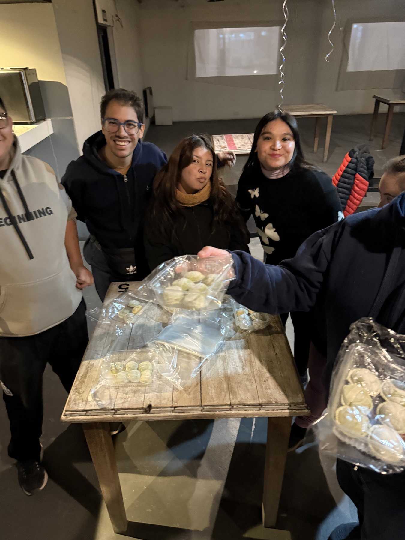 Mesa cubierta de paquetes de pastas frescas terminadas, con parte del equipo alrededor.