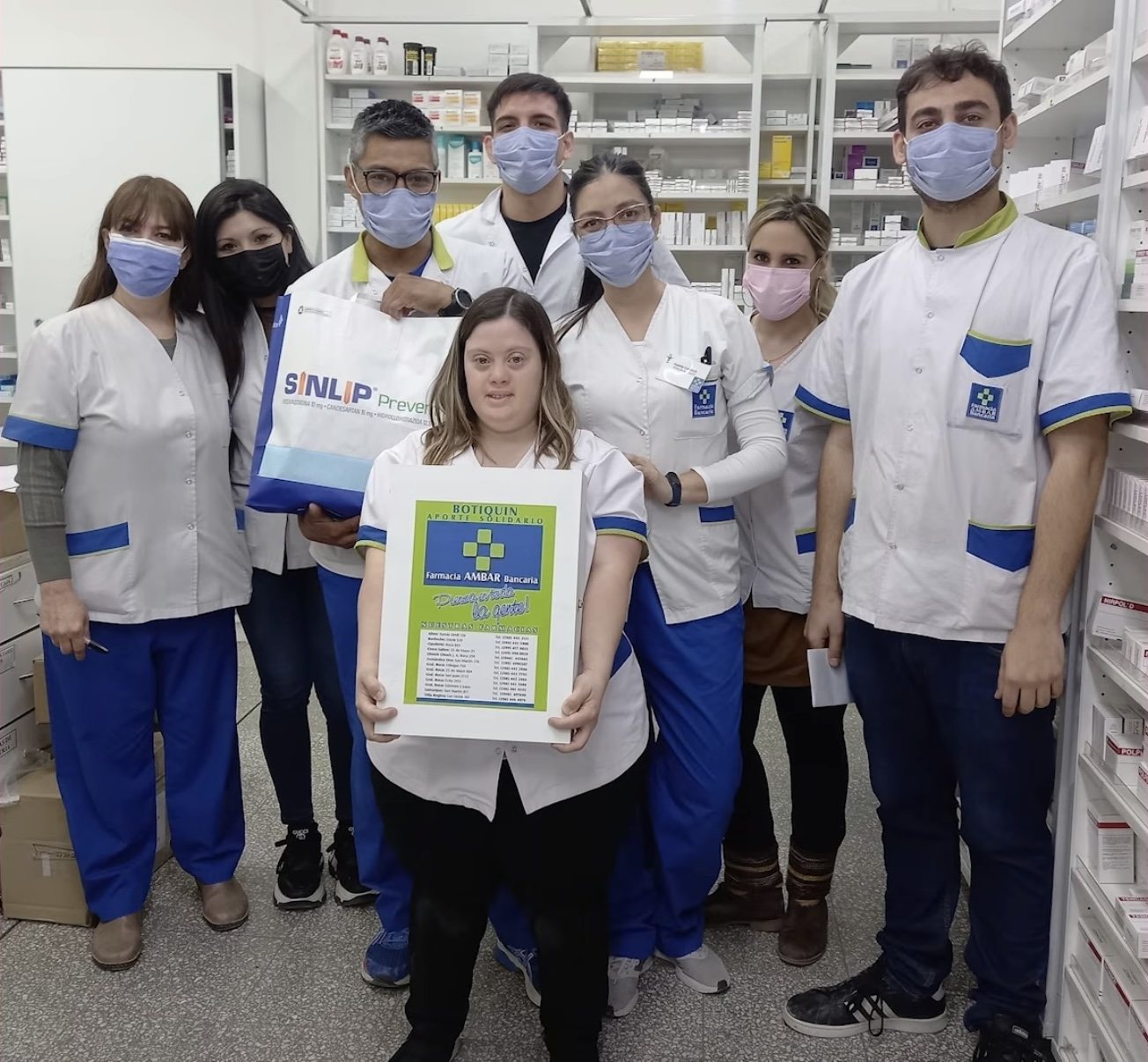 Equipo de una farmacia con guardapolvos blancos junto a una alumna de Fundación Kano.